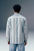 Person wearing a striped shirt and jeans from behind on a gradient background