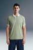 Three-quarter front shot of a man standing still, wearing an olive green polo shirt with white trim details, paired with dark blue trousers.