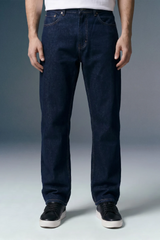 Person wearing dark blue jeans on a gray background