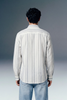 Man wearing a striped shirt and jeans against a gray background