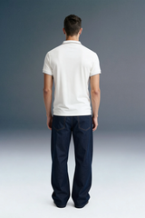 Full-length rear view of a man standing still, showing a white polo shirt tucked slightly into dark navy blue pants.