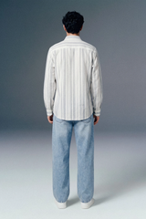 Person wearing a striped shirt and jeans from behind on a gray background
