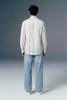 Person wearing a striped shirt and jeans from behind on a gray background