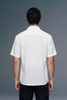 Man wearing a white short-sleeve shirt against a gray background