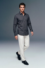 Man wearing a dark gray shirt and white pants on a plain background