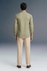 Person wearing a green shirt and beige pants against a gray background