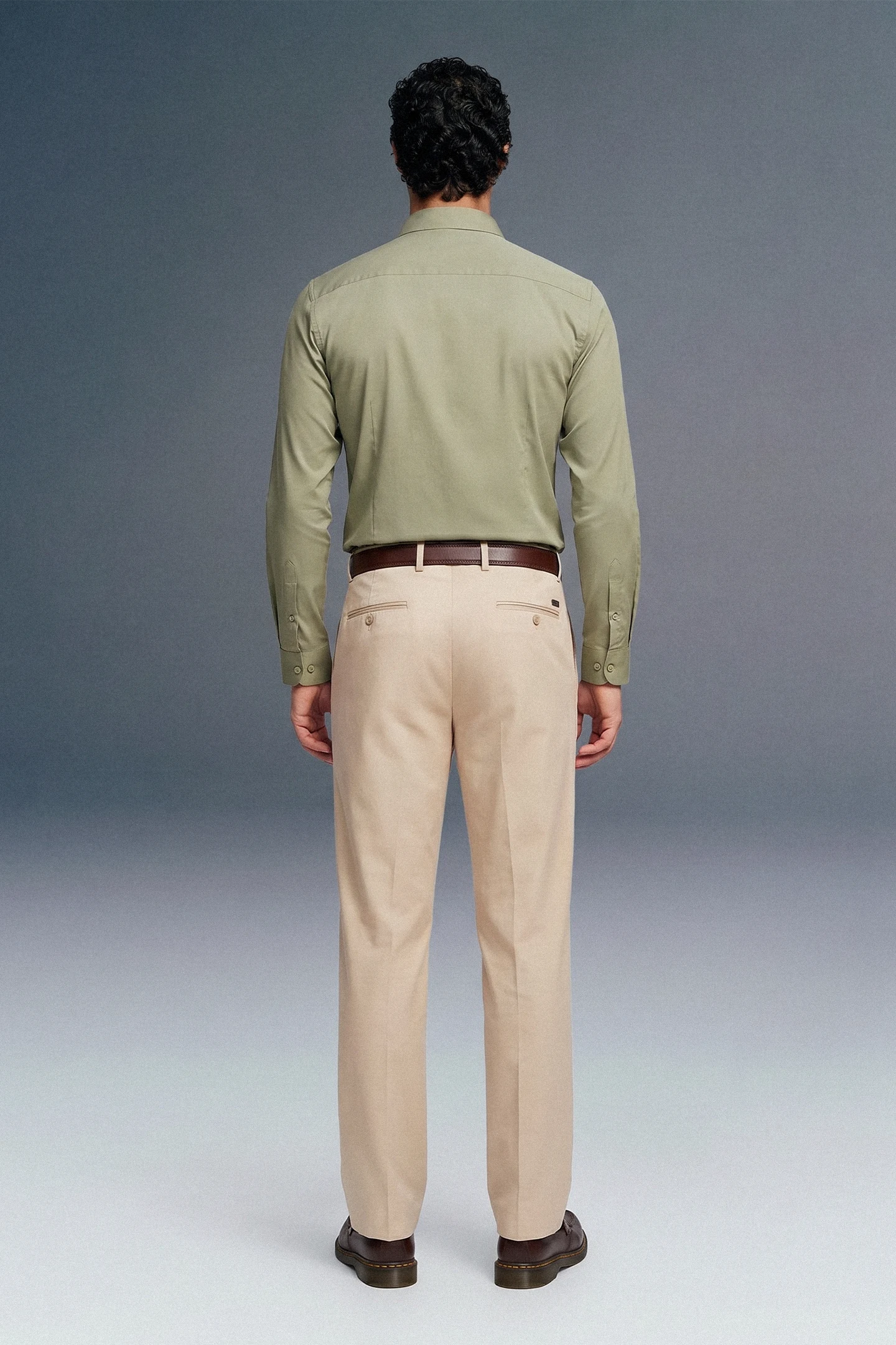 Man wearing a green shirt and beige pants against a gray background