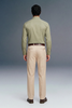 Man wearing a green shirt and beige pants against a gray background