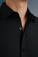 Close-up of a black shirt with a collar and buttons on a gray background