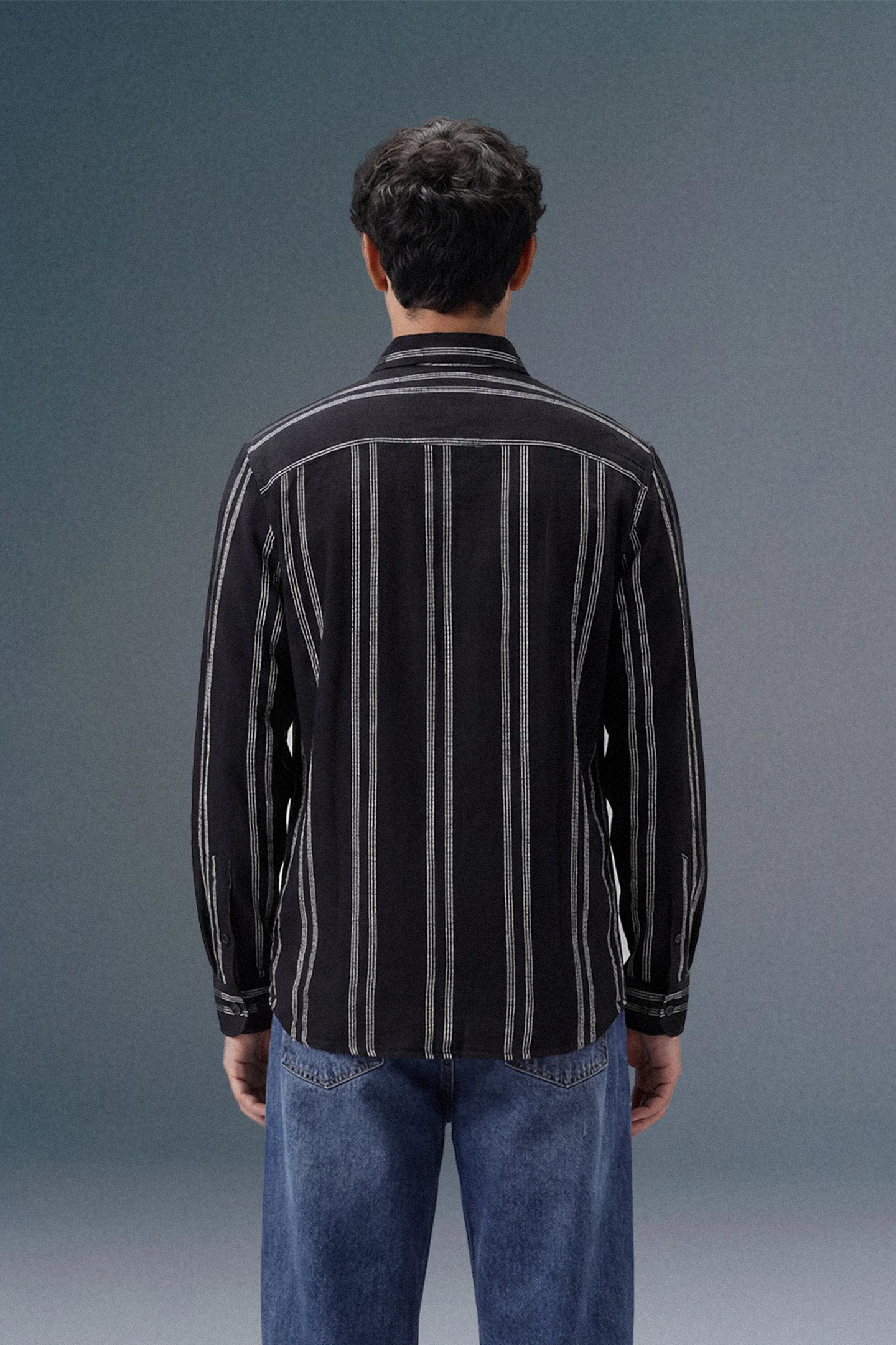 Person wearing a black and white striped shirt against a gray background