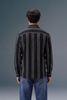 Person wearing a black and white striped shirt against a gray background