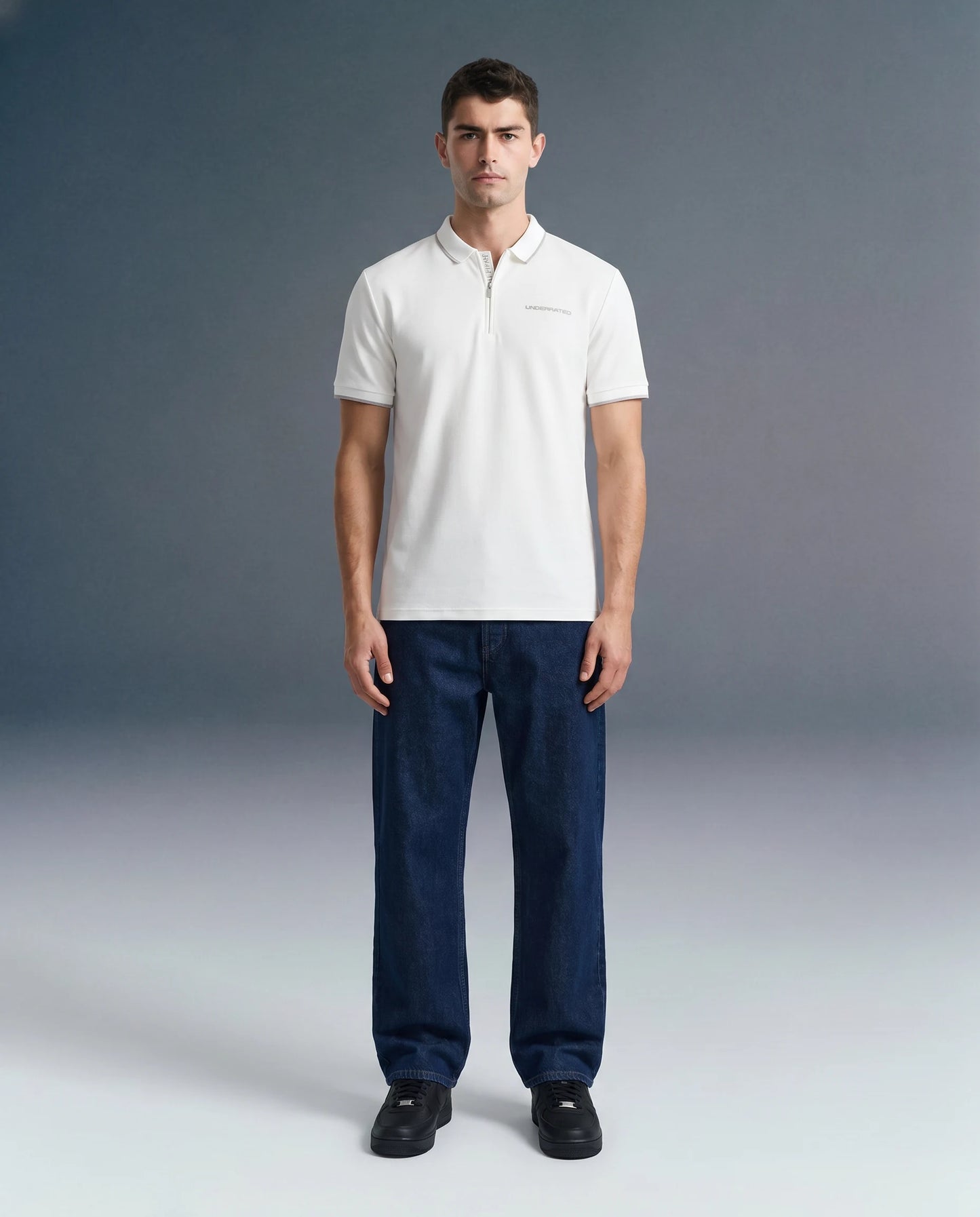 Full-length front view of a man standing straight and looking ahead, wearing a white polo shirt paired with dark blue trousers.