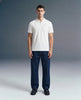 Full-length front view of a man standing straight and looking ahead, wearing a white polo shirt paired with dark blue trousers.