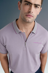 A close-up shot from the chest up of a man looking forward, highlighting the open collar detail and pink contrast trim on a light purple polo shirt.