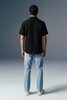 Person wearing a black shirt and light blue jeans against a gray background