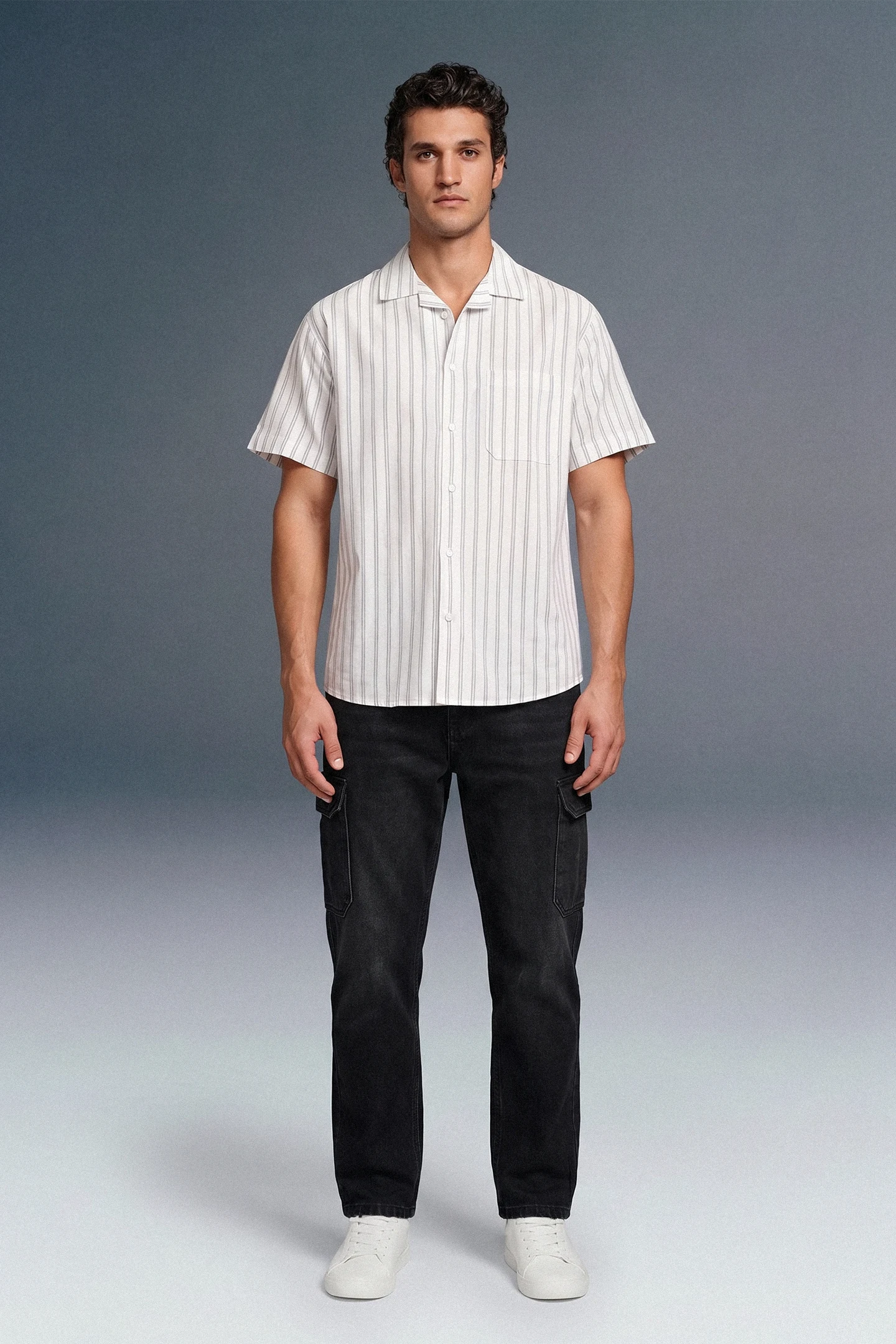 Man wearing a white striped shirt and black pants against a gray background