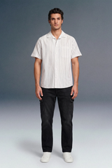 Man wearing a white striped shirt and black pants against a gray background