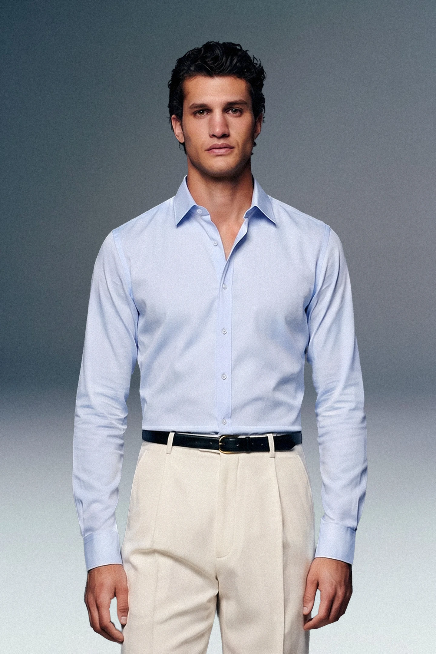 Man wearing a light blue dress shirt and beige pants against a gray background