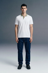 Full-length front view of a man standing straight and facing forward, wearing a white polo shirt with an olive green collar, paired with dark navy blue trousers.
