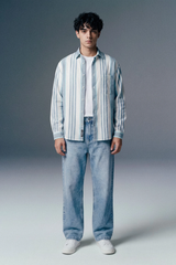 Person wearing a striped shirt and jeans against a gray background