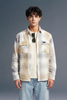 Man wearing a plaid shirt and jeans against a gray background