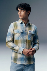 Man wearing a plaid shirt with a brand logo on a gray background