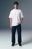 Man wearing a plain white t-shirt and dark pants on a gray background