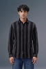 Man wearing a black and gray striped shirt against a gray background