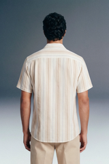 Man wearing a beige striped shirt and pants against a gray background