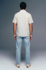 Person wearing a striped shirt and jeans from behind on a gray background
