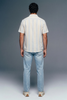 Person wearing a striped shirt and jeans from behind on a gray background