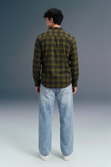 Person wearing a green plaid shirt and light blue jeans against a gray background