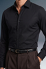 Black dress shirt worn by a person with a blurred background