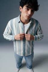 Man wearing a striped shirt and jeans against a gray background