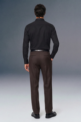 Man wearing a black shirt and brown pants against a gray background