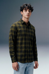 Man wearing a green plaid shirt against a gray background