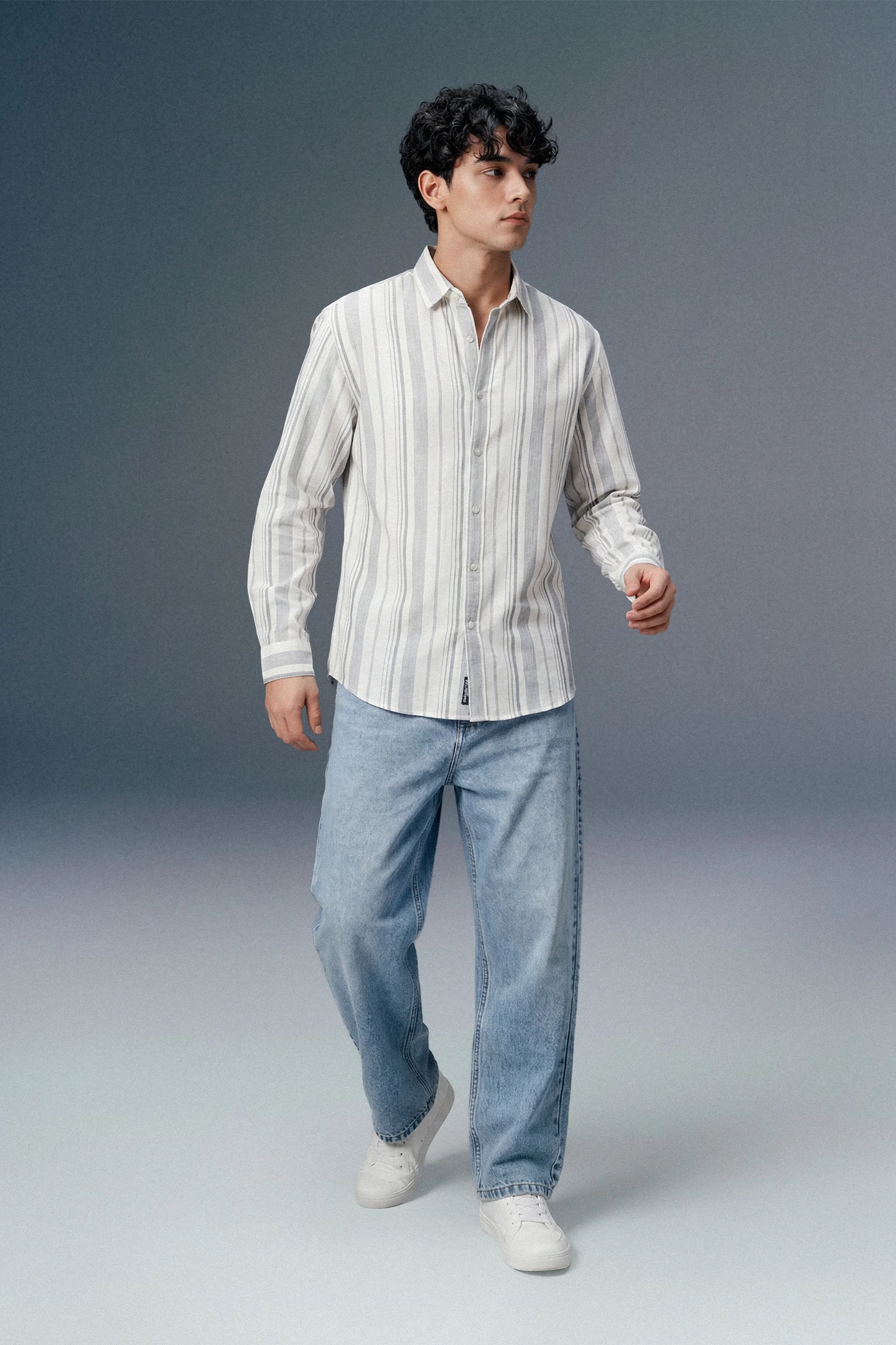 Man wearing a striped shirt and jeans against a plain background