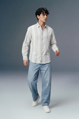 Man wearing a striped shirt and jeans against a plain background