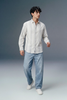 Man wearing a striped shirt and jeans against a plain background