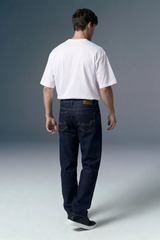 Person wearing a white t-shirt and dark jeans against a gray background