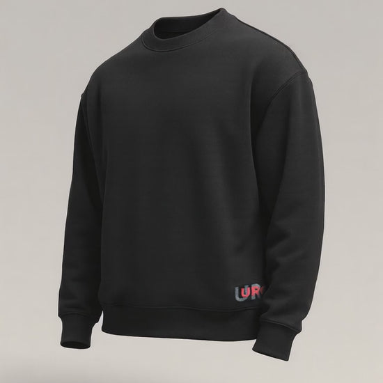 Black oversized crewneck sweatshirt with a small, colorful URC logo print near the left hem.