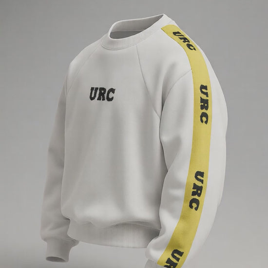 White sweatshirt with a high neck, black URC logo on the chest, and a bold yellow racing stripe on the sleeve with repeated black text.
