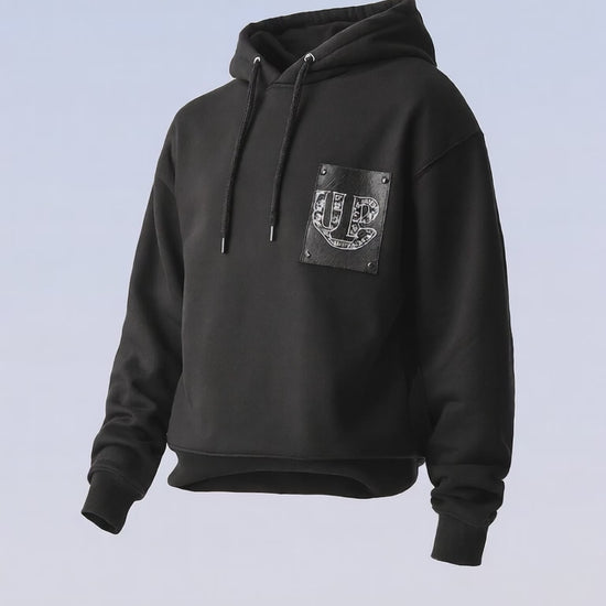 Black pullover hoodie with drawstrings and a subtle dark text print on the chest.