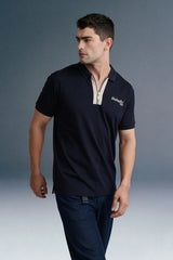 A dynamic, close-up angled shot from the chest up focusing on the arm and torso of a man leaning forward in a navy blue polo shirt with beige collar detailing.