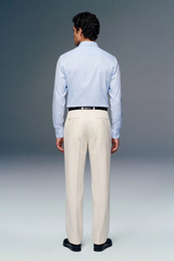 Man wearing a light blue dress shirt and beige pants against a gray background