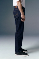 Person wearing dark blue jeans and black shoes on a gray background
