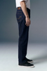 Person wearing dark blue jeans and black shoes on a gray background