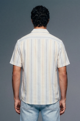 Person wearing a striped shirt and jeans against a gray background