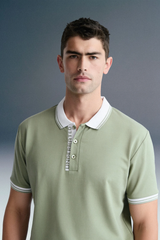 A medium close-up, front-facing shot of a different man looking forward, wearing an olive green polo shirt with a contrasting white collar and white sleeve cuffs.