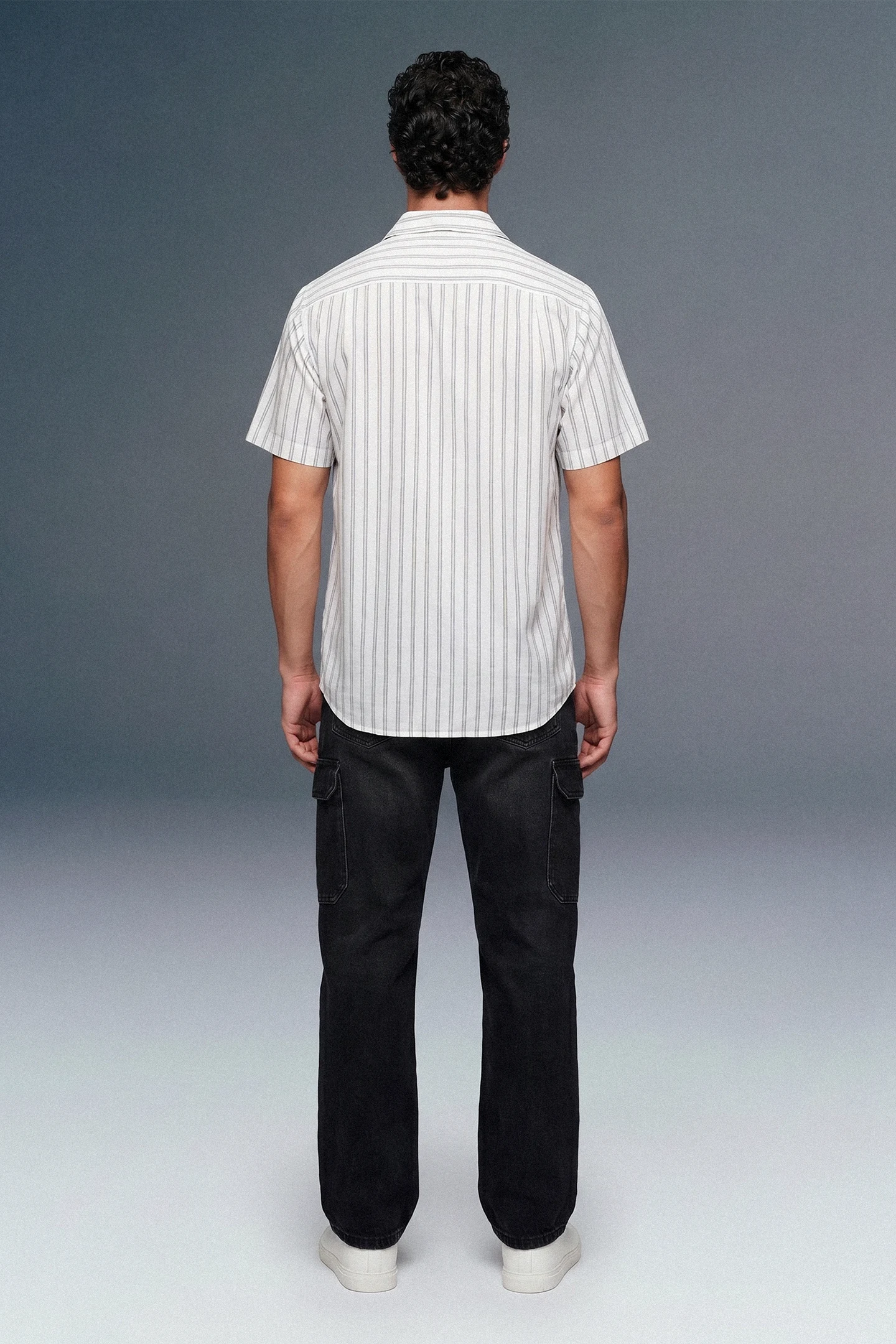 Person wearing a white striped shirt and black pants against a gray background